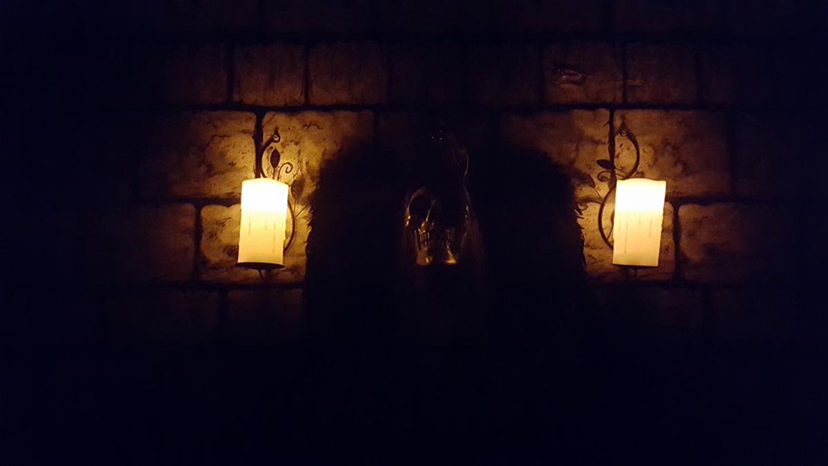 A terrifying skull in the shadows, flanked by two flickering candles