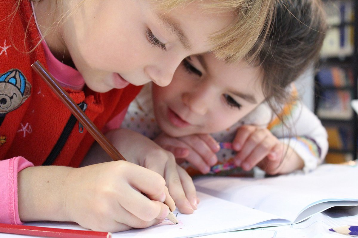Two young girls looking closely at their homework