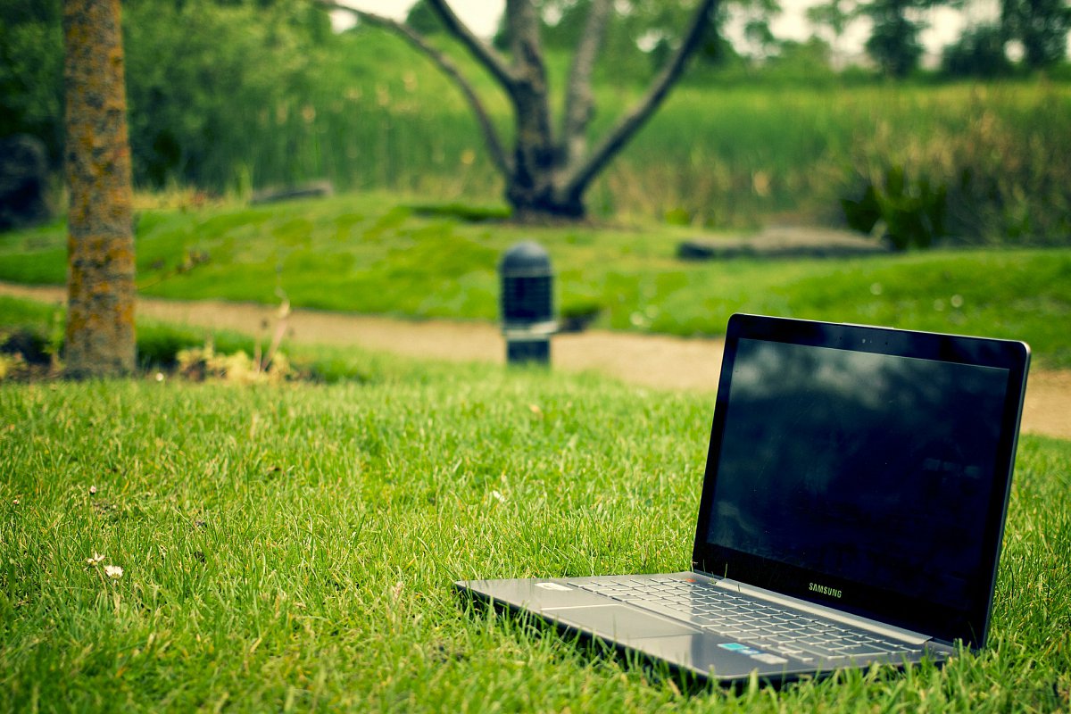 A laptop sitting outside in the grass