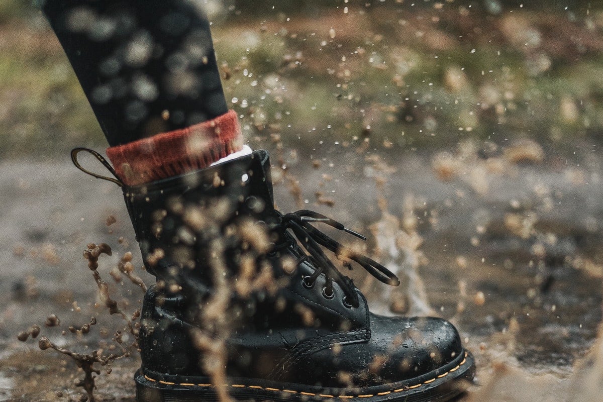 Black boot tromping through the mud, splashing water everywhere