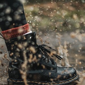 Black boot tromping through the mud, splashing water everywhere